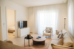 Una sala de estar moderna con televisor, sofá, sillón y una mesa de centro.