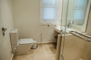 Un baño pequeño y funcional con inodoro, bidé y cabina de ducha de vidrio.
