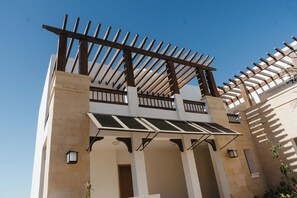 Un edificio con una estructura de pérgola de madera, paneles solares y un cielo azul despejado.