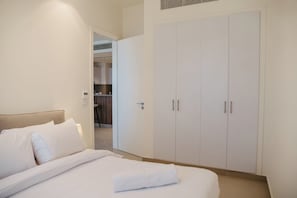 Un dormitorio con cama, armario y una pequeña cocina al fondo.