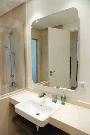 Un baño con ducha, lavabo y espejo.