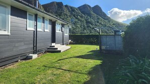 Et moderne hus med to etager, en velplejet græsplæne og et bjerg i baggrunden.