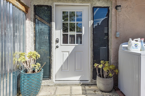 A white door with a window, a potted plant, and a washing machine. - Walk to University & 4th Ave: Tucson Studio (Tucson)