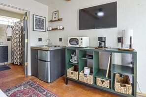 A compact kitchen with a refrigerator, a toaster, a coffee maker, and a flat-screen TV mounted on the wall. - Walk to University & 4th Ave: Tucson Studio (Tucson)