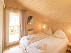 A room with two beds, a window with curtains, a framed picture on the wall, and a small table. - One-bedroom Cabin (Sankt Georgen am Kreischberg)