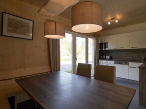 A modern kitchen with white cabinets, a dark countertop, and a hanging light fixture. - One-bedroom Cabin (Sankt Georgen am Kreischberg)