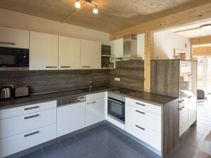 A modern kitchen with white cabinetry, a dark countertop, and a stainless steel oven. - One-bedroom Cabin (Sankt Georgen am Kreischberg)