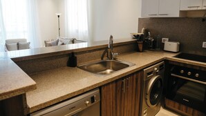 Una cocina moderna con lavavajillas integrado, un fregadero, una estufa y un tostador.