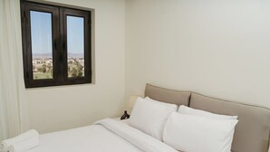 Una habitación de hotel con cama, ventana con vistas y lámpara.