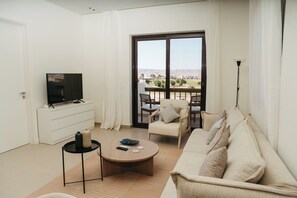 Ein modernes Wohnzimmer mit Fernseher, einer Couch, einem Couchtisch und einem Balkon mit Blick.