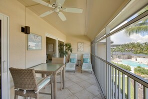 A balcony with wicker furniture, a ceiling fan, and a view of a swimming pool. - Access to Pool & Sanibel Beach: Resort-Style Condo (Sanibel)
