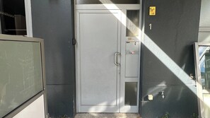 Een grijze deur met een hendel, een klein bedieningspaneel en een geel bord met cijfers.
