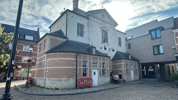 Een historisch gebouw met een stenen gevel, een hoingang en een straat met kinderaardewerktegels.