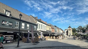 Een straat met winkels en een klokkentoren op de achtergrond.