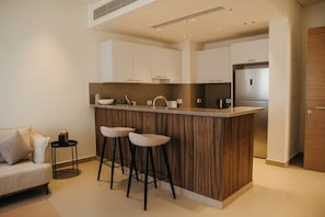 A modern kitchen with a central island, bar stools, and a built-in oven. - 1 BR Ancient Sands Residence (Hurghada)