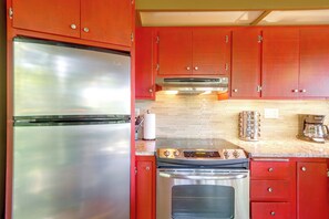 A kitchen with red cabinets, a stainless steel refrigerator, a built-in oven, and a coffee maker. - Boater’s Paradise! Hiwassee Lake Treetop Retreat (Murphy)