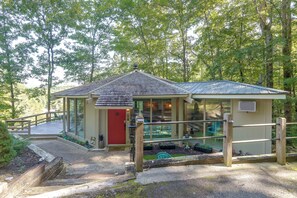 A small, single-story building with a red door, a covered porch, and a metal railing.
