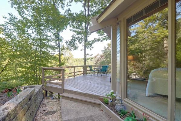 A wooden deck with a table and chairs, surrounded by trees.