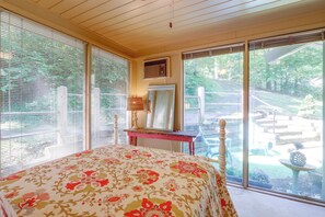 A bedroom with a bed, a dresser, a mirror, and a view of a garden through a sliding glass door.