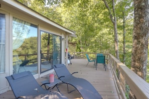 A covered outdoor deck with lounge chairs, a table, and a grill area.