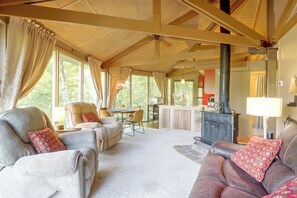 A spacious living room with a high ceiling, a fireplace, and a dining area with a table and chairs.
