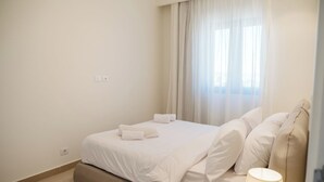 Hotellihuone, jossa on sänky, yöpöytälamppu ja ikkuna, jossa on verhot.
