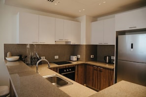 Una cocina moderna con armarios blancos, un refrigerador de acero inoxidable y una encimera de granito.