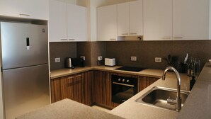 Una cocina moderna con refrigerador de acero inoxidable, gabinetes de madera, horno empotrado y pileta con grifo.