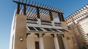 Un edificio con una estructura de pérgola de madera, paneles solares y un cielo azul despejado.