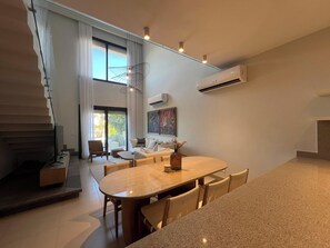 A modern interior with a dining area, a staircase, and a living space with a sofa and a painting.