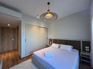 A modern bedroom with a large bed, a hanging light fixture, and a wardrobe.