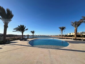 A swimming pool with a clear view of the sea and buildings in the background.