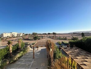 A hotel with a view of a landscaped area, palm trees, and a distant building.
