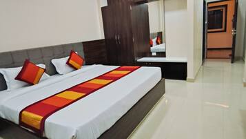 A hotel room with a bed, a ceiling fan, an air conditioning unit, and a bathroom door.
