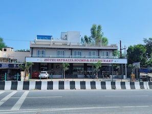 A hotel with a signboard for 'HOTELVATSALYAROMES&RESTAURANT' and a visible car parked in front.