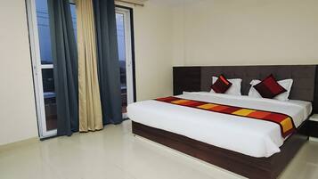 A hotel room with a bed, curtains, a ceiling fan, and a view through a window.