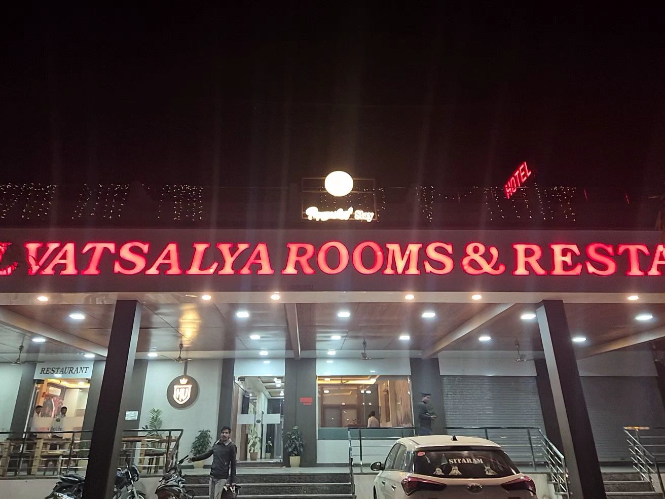 A hotel entrance with a sign for 'Vatsalya Rooms & Restaurant' and a visible 'Hotel' sign.