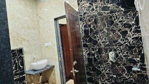 A bathroom with a marble sink, a toilet, and a shower area. - Papaya Leaf Stay (Nathdwara)