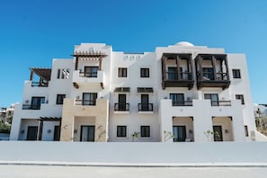 Un hotel de varios pisos con balcones, techo plano y cielo despejado.