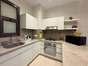 Una cucina moderna con mobili bianchi, lavello in acciaio inossidabile e forno integrato.
