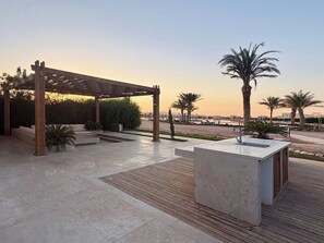 Ein Außenbereich mit Terrasse, einer Pergola, Sitzgelegenheiten und einem Wasserspiel.