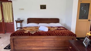 A neatly made bed with a floral bedspread, a wooden headboard, and a small bedside table with a framed photo.