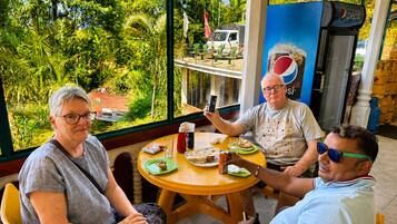 Three people seated at a table with a view of greenery outside.