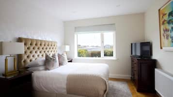 A bedroom with a large bed, a television, and a window with a view.