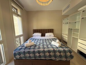 Ein Schlafzimmer mit einem Bett, zwei Kissen, einer Steudecke, einem Handtuch und einem Kleiderschrank.