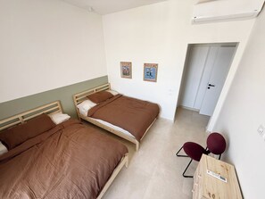 Ein Zimmer mit zwei Betten, einem Schreibtisch und einem Stuhl.