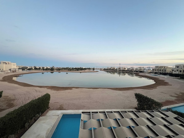 A large oval-shaped pool with a sandy edge, surrounded by a low-rise residential area.