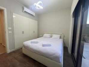 A bedroom with a bed, a wardrobe, an air conditioning unit, and a window.