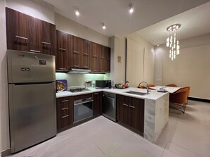 A modern kitchen with dark wood cabinets, stainless steel appliances, and a central island with a sink. - Luxury 4BR Cyan Villa • Private Pool (Hurghada 2)