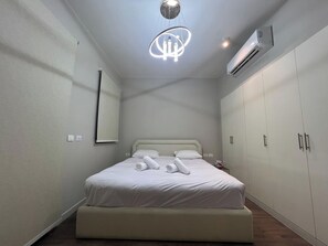 A hotel room with a bed, a bedside table, a mirror, an air conditioning unit, and a wardrobe. - Luxury 4BR Cyan Villa • Private Pool (Hurghada 2)